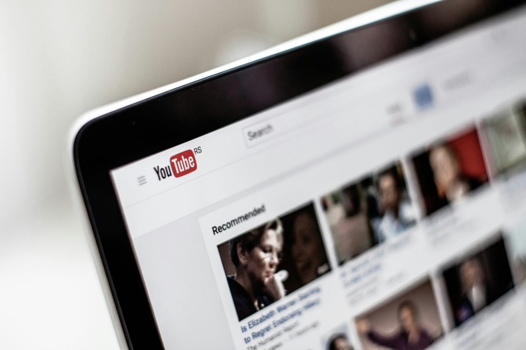 Close-up of laptop showing YouTube homepage with recommended videos and search bar